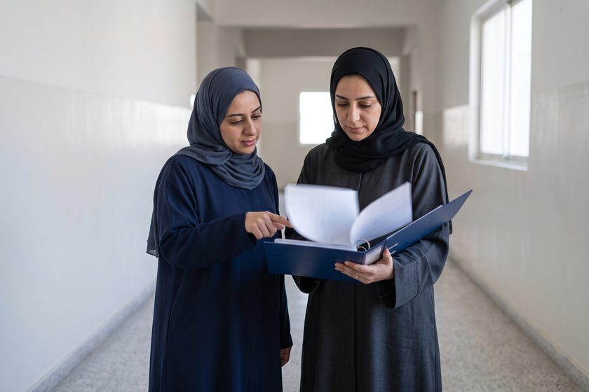 معلّمتان تراجعان ملفًّا في ممرّ المدرسة